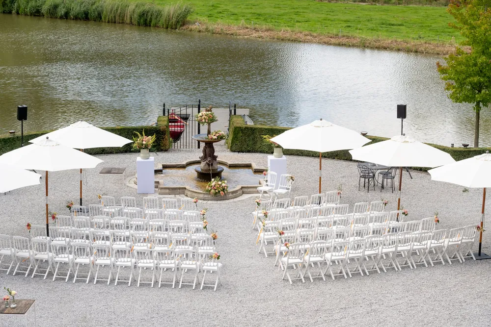 La cérémonie laïque prête au bord d'un étang, chaises blanches et parasols